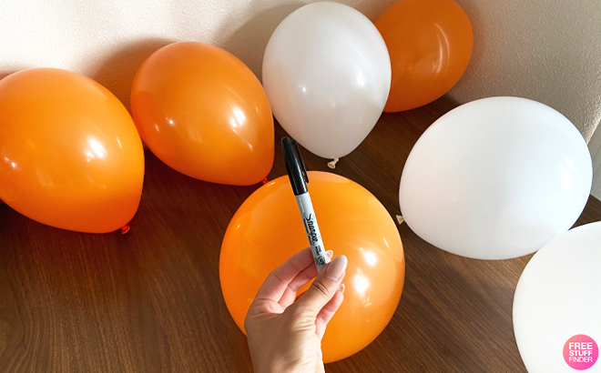 Person Holding a Sharpie with Balloons in the Background