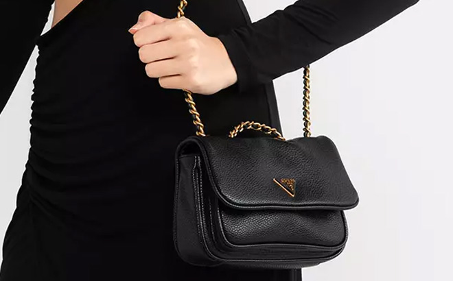 Woman is Holding Guess Becci Mini Convertible Chain Flap Crossbody in Black Color