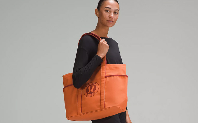 Woman is Wearing a Lululemon Daily Multi Pocket Canvas Tote Bag in Terra Orange Color