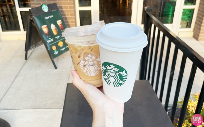 a Hand Holding Two Cups of Starbucks Coffee