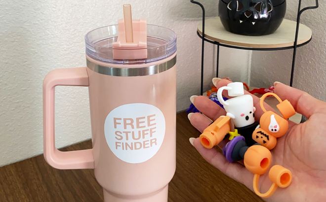 hand holding straw covers next to an insulated tumbler