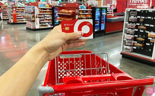 A Person Holding a Target RedCard Above a Target Shopping Cart in the Target Store