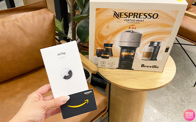 Hand Holding Apple AirTags 4 Pack and Amazon Gift Card with Nespresso Coffee Machine on the Table