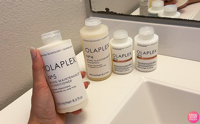 Hand Holding Olaplex No 5 Bond Maintenance Conditioner with Other Olaplex Products in the Background