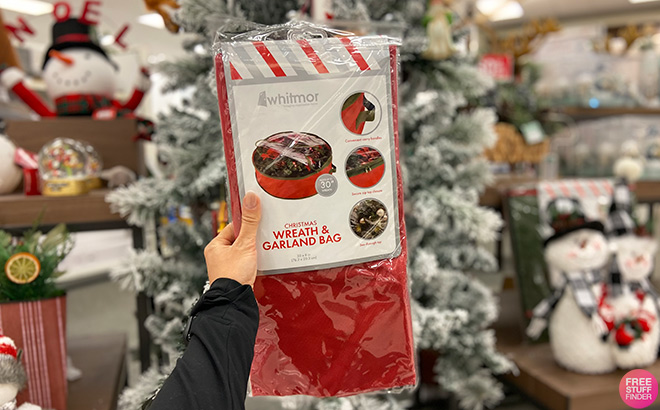Hand Holding Whitmor Christmas Wreath Garland Storage Bag in a Store Aisle