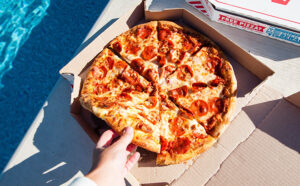Hand Holding a Slice of Dominos Pizza in a Box