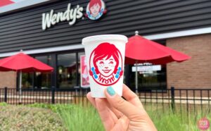Hand holding Jr Frosty in front of Wendys Store