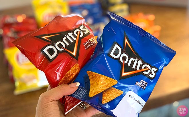 Hand holding two Doritos Packs