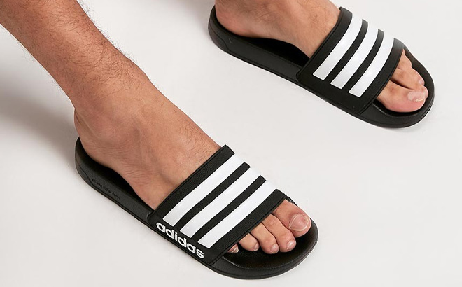 Man is Wearing Adidas Mens Adilette Shower Slides in Core Black and Cloud White Color
