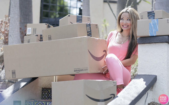 A Person Sitting on Stairs In Front of a Home and Holding Amazon Delivery Boxes
