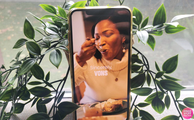 A Smartphone with the Vons App Preview on the Screen in Front of a Green House Plant