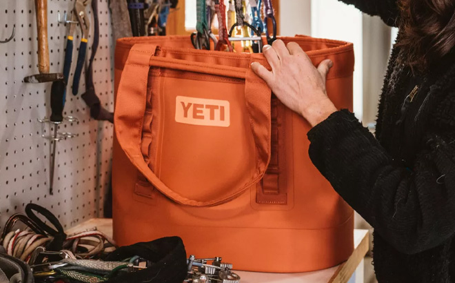 Woman is Packing into YETI Camino 35 Carryall Tote Bag in High Desert Clay Color