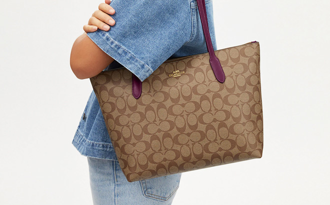 Woman is Wearing Coach Zip Top Tote In Signature Canvas in Gold Khaki and Deep Berry Color Woman is Wearing Coach Zip Top Tote In Signature Canvas in Gold Khaki and Deep Berry Color