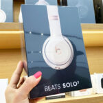a Woman Holding Beats Solo 3 Headphones in Store