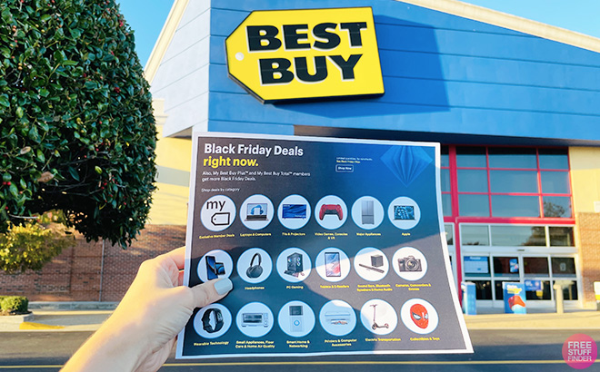A Hand Holding a Best Buy Black Friday Ad in Front of a Best Buy Store