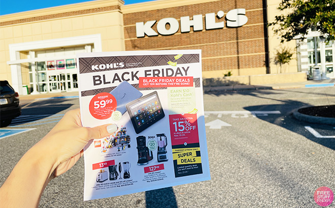 A Hand Holding the Kohls Black Friday Ad with a Kohls Store in the Background