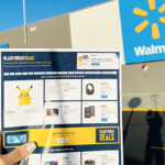 A Hand Holding the Walmart Black Friday Ad with a Walmart Store in the Background