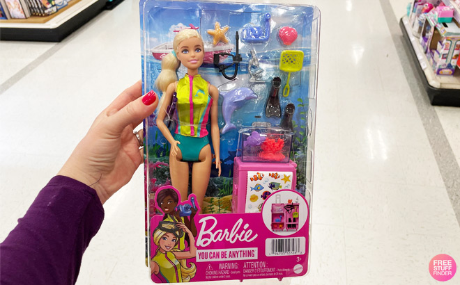 A Person Holding a Barbie Marine Biologist Doll Playset in a Store Aisle