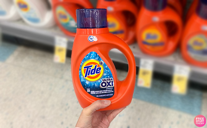 Hand Holding Tide Ultra Oxi in a Store Aisle