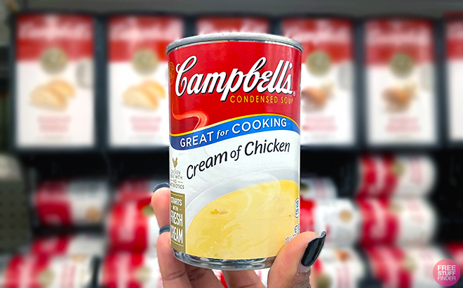 Hand holding oen can of Campbells Condensed Cream of Chicken Soup