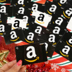 Tina Holding Amazon Gift Card with Many More Amazon Gift Cards in the Background