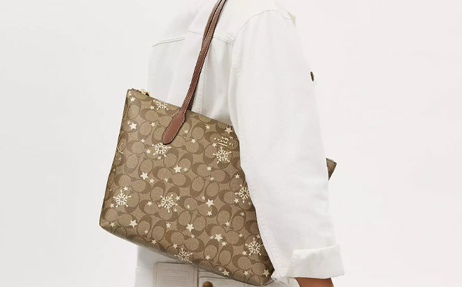 Woman is Wearing Coach Zip Top Tote In Signature Canvas With Star And Snowflake Print
