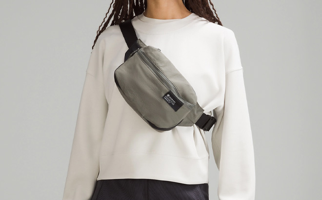 Woman is Wearing Lululemon Clean Lines Belt Bag in Gray Sage Color