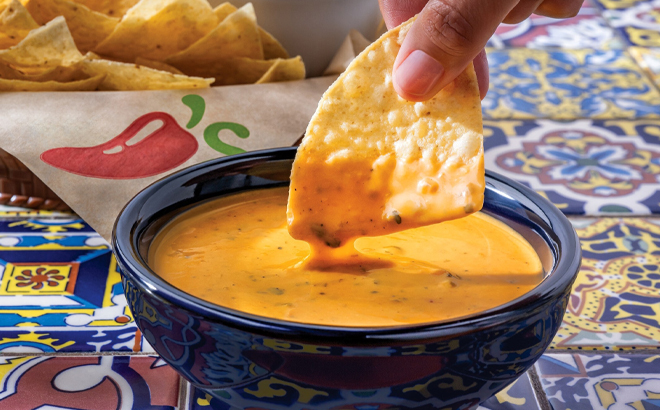 A Hand dipping a Chip into a Chilis Southwestern Queso
