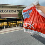 A Person Holding a Clear The Rack Sale in Front of Nordstrom Rack Store