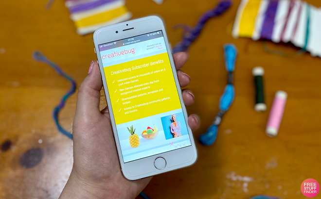 A Person Holding a Phone with Creativebug on the Background