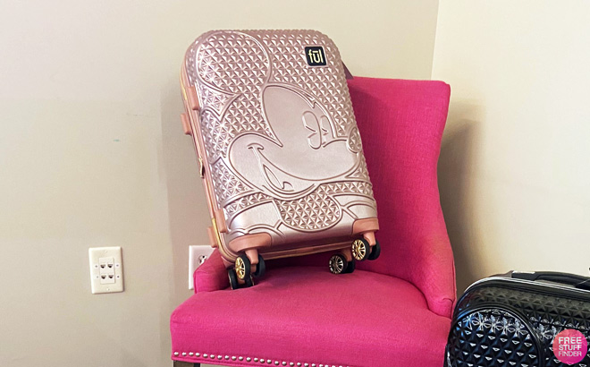 FUL Disney Mickey Mouse 29 Inch Rolling Luggage in Rose Gold on a Chair