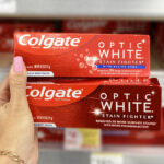 Hand Holding Two Colgate Optic White Stain Fighter Toothpastes