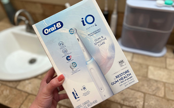 Hand Holding a Box of Oral B iO Toothbrush in a Bathroom