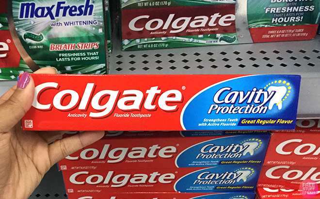 Hand holding one Colgate Cavity Protection Toothpaste