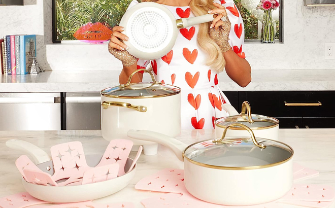 Paris Hilton Holding a Pot from Her Epic Nonstick12 Piece Cookware Set in Cream Color