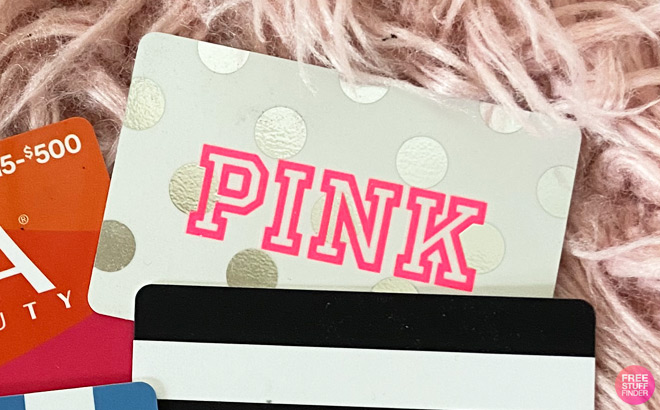 Victorias Secret PINK Gift Card on Blanket Surrounded by Other Gift Cards