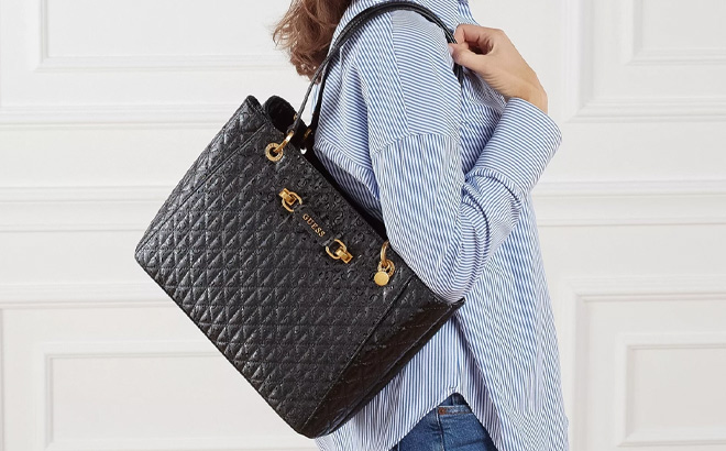 Woman is Wearing Guess Aventa Noel Tote in Black Color Woman is Wearing Guess Aventa Noel Tote in Black Color