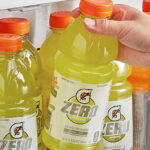 A Hand Grabbing Gatorade Zero Sugar Thirst Quencher in Lemon Lime from a Shelf Filled with Gatorade