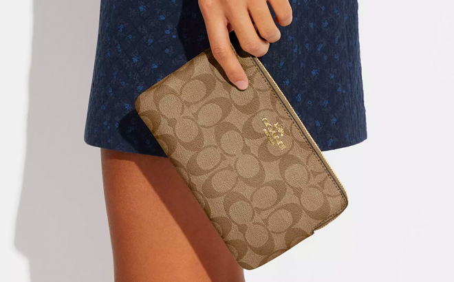 A Person Holding Large Zip Corner Coach Wristlet in Signature Canvas