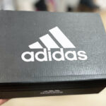 A Person Holding a box of Adidas