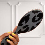 A Person holding the Wet Brush Original Detangler Hair Brush in Dark Gray Leopard