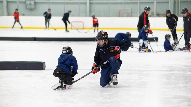 Coach Training a Kid on how to Play Ice Hockey on USA Hockey Try Hockey FREE Day