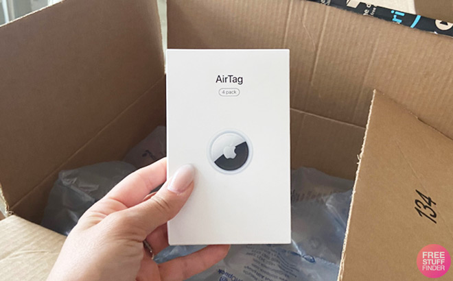 Hand Holding Apple Airtag 4 Pack in Front of Amazon Box