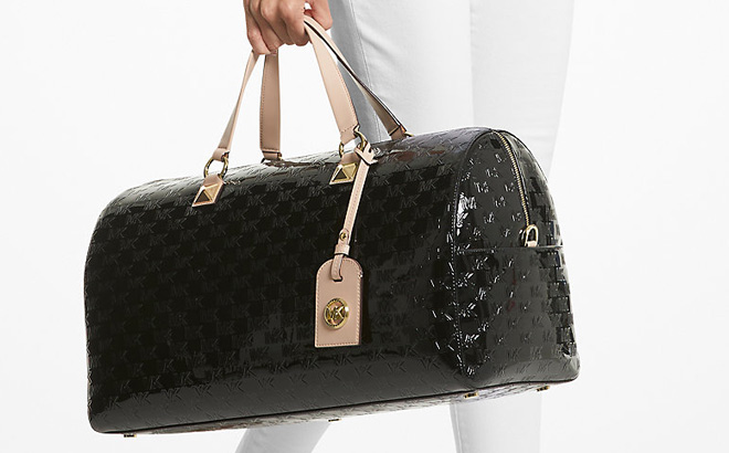 Hand Holding Michael Kors Grayson Extra Large Logo Embossed Patent Weekender Bag in Black Color