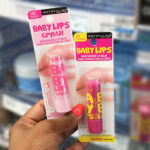 Hand holding two Maybelline Baby Lips Lip Balms