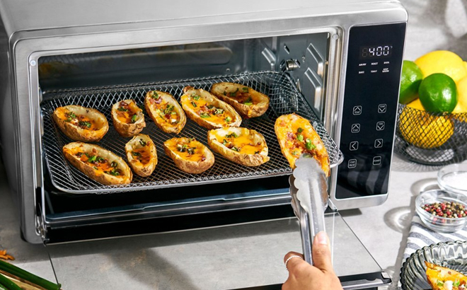 Woman Taking Out Food from Bella Pro Series 6 Slice Air Fryer Toaster Oven with Rotisserie
