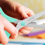 A Hand Cutting a Paper Using Scissors