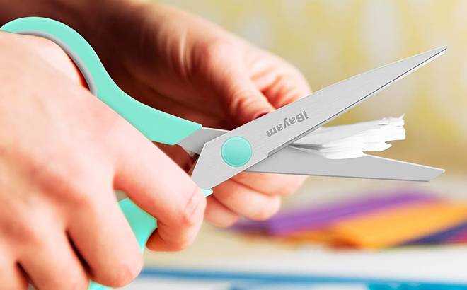 A Hand Cutting a Paper Using Scissors