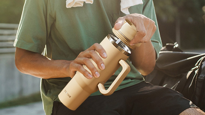 A Person Holding and Opening the Lid of a Carote 40 Ounce Insulated Tumbler
