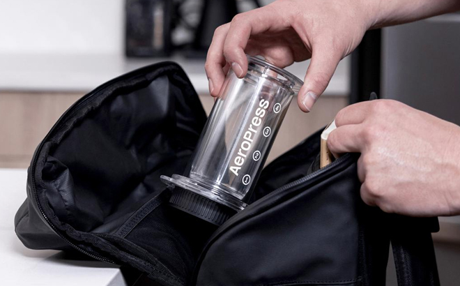 A Person Putting the AeroPress Tinted 3 in 1 Brewing Coffee Press in a Duffel Bag A Person Putting the AeroPress Tinted 3 in 1 Brewing Coffee Press in a Duffel Bag
